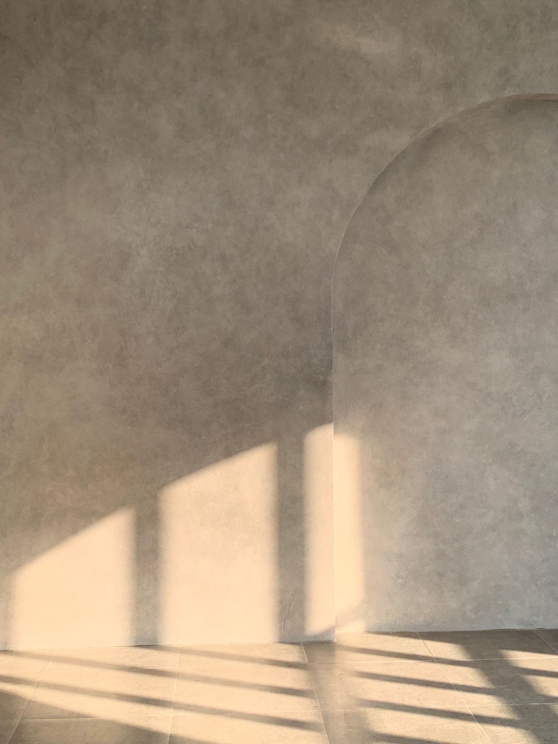 A warm plaster wall with an arched opening, raking afternoon light